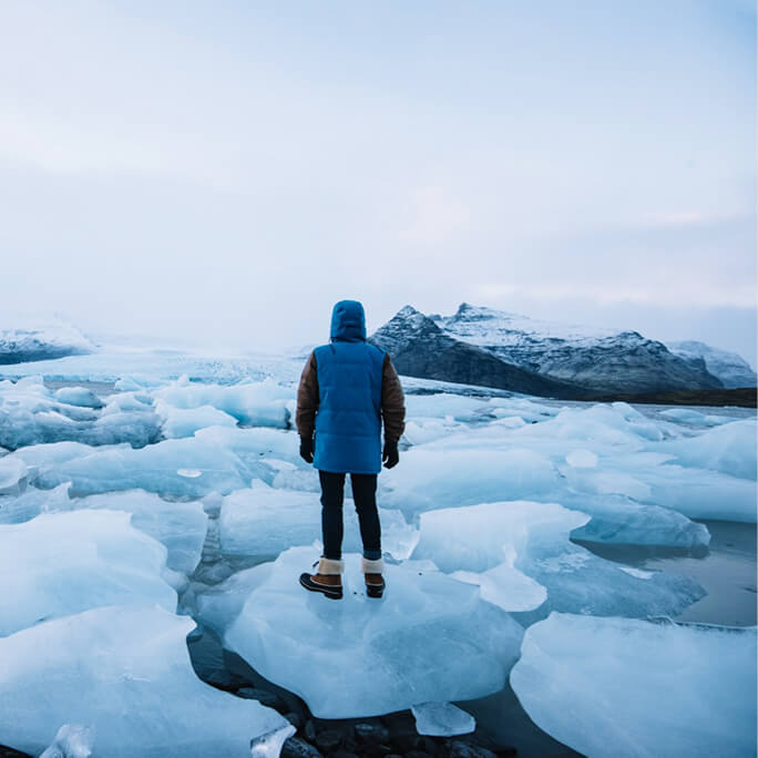 A person standing on a block of ice that is melting